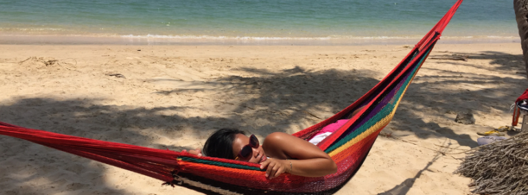a girl in the colorful hammock on the beach