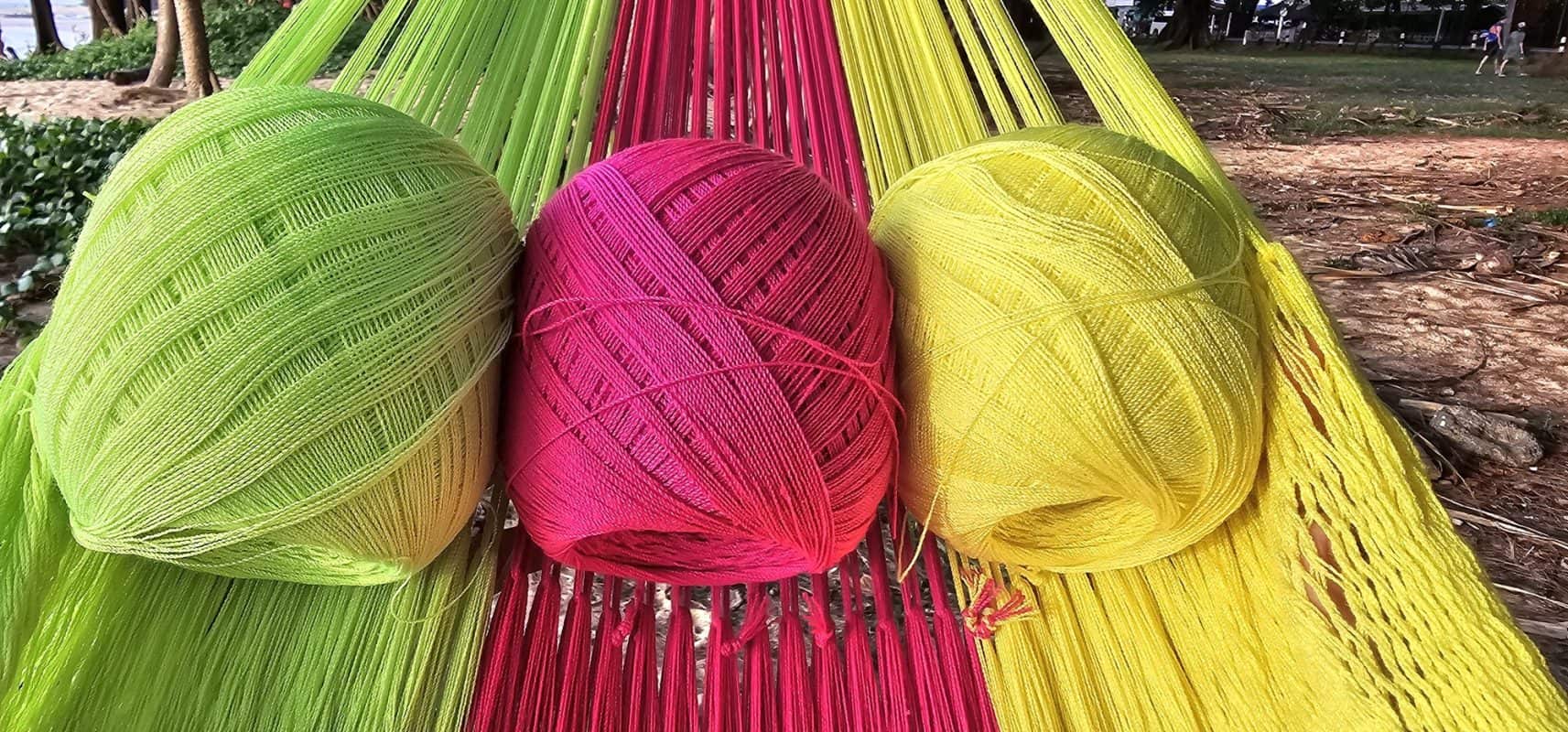 Three balls of yarn in neon green, hot pink, and yellow, showing the colors used for the Funky woven hammock.