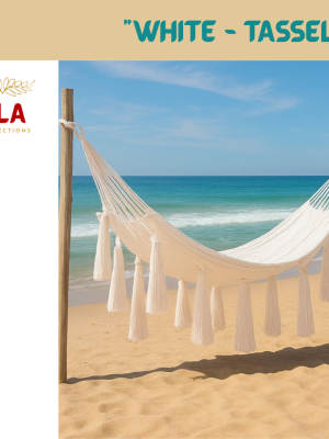 White Hammock with Large Tassels on a beach. Luxurious, hand-woven hammock in bright white for a boho, tropical look. Perfect for beach, garden, or patio lounging.