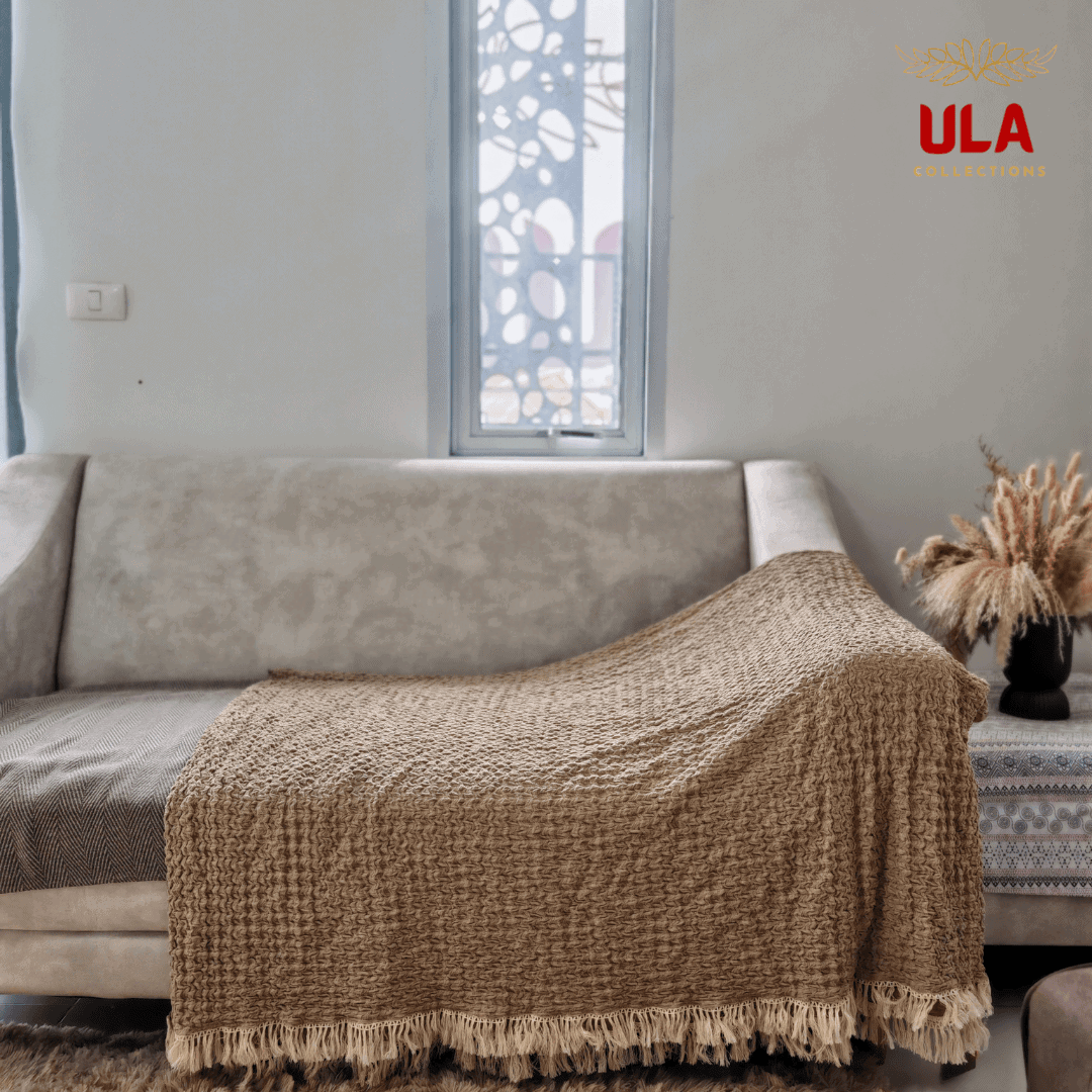 Almond ruffle throw blanket with cream tassels draped over a sofa for full coverage