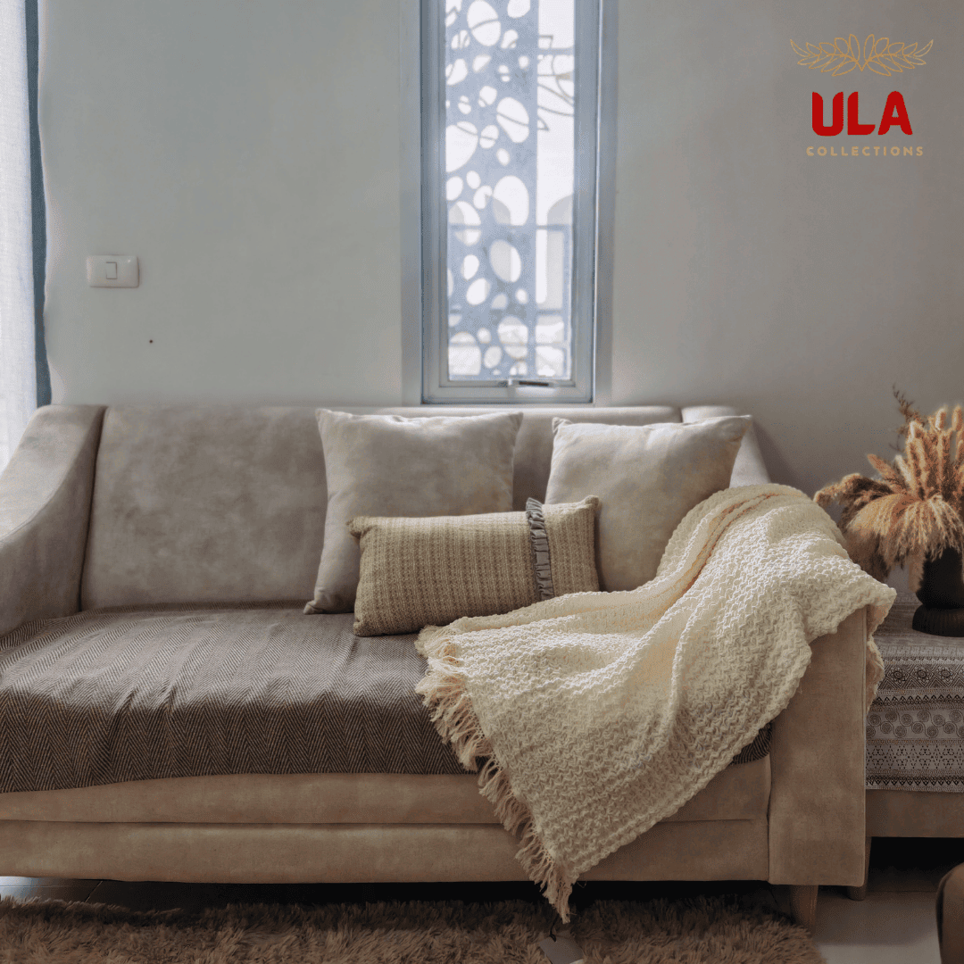 Cream textured throw blanket draped over the arm of a beige couch with pillows