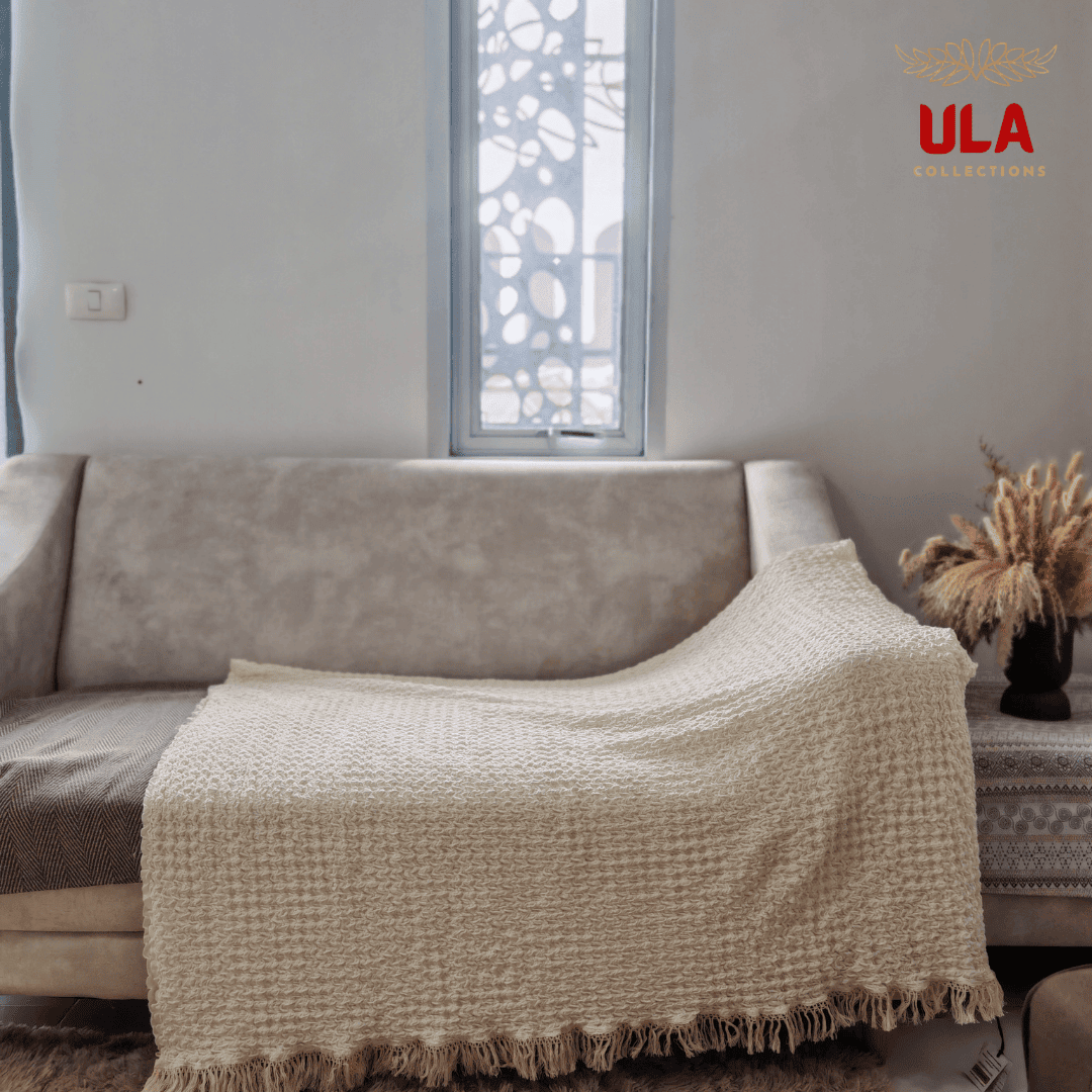 Buttercream ruffle throw blanket with tassels draped fully over living room couch