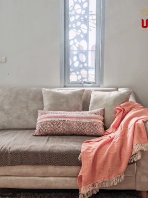 Peach lightweight throw blanket casually draped over the arm of a neutral living room couch