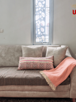 Decorative Sulu peach fringed throw blanket styled neatly on a beige couch with pillows