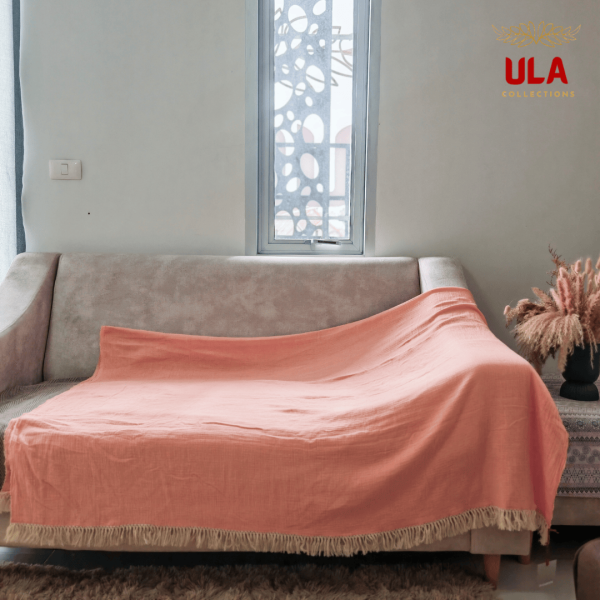 Peach Sulu crinkle gauze throw blanket with fringe fully covering a sofa